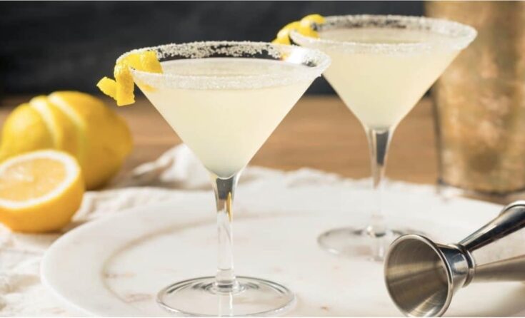 Lemon Drop Cocktail in Martiniglas neben Zitrone und Jigger